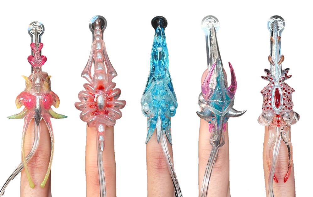 Onycho Lab — five fingertip prostheses in pink, peach, blue, magenta and crimson, mounted upright in a row